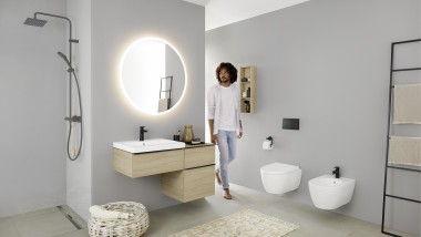 Mann läuft ins Bad mit Waschtisch, WC, Bidet und Badmöbeln aus der Badserie Geberit iCon Mann läuft ins Bad mit Waschtisch, WC, Bidet und Badmöbeln aus der Badserie Geberit iCon